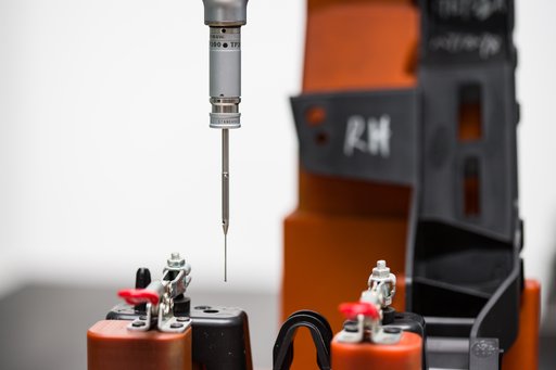 A measurement probe positioned above a small metal component held in a fixture.